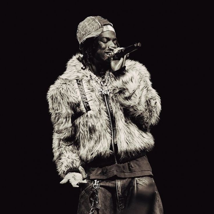 Nigerian Artist Rema, holding a mic and performing live on stage.